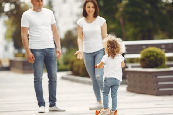 Happy family spending quality time together outdoors, with a child riding a skateboard.
